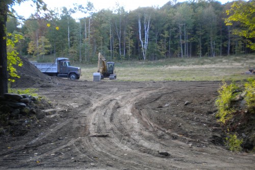 Muddy field in central vermont with work vehicles during new home build project by allied contractors