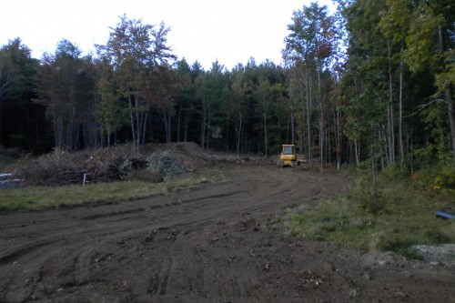 Muddy field in central vermont with bulldozer during initial stages of new home build project by allied contractors