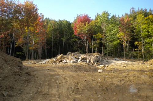 central vermont field with pile of debris and early autumn trees during new home build project by allied contractors