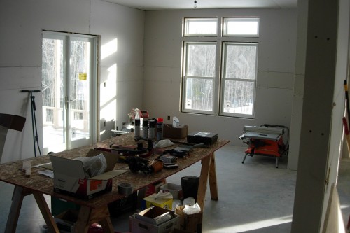 Room with tools on a work bench and installed green window during allied contractors central vermont home rebuild project