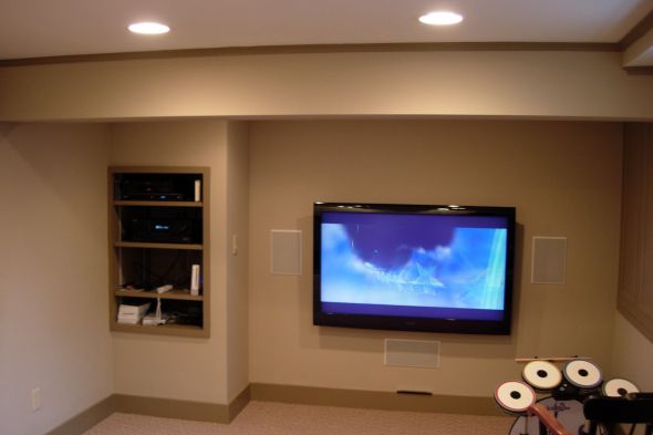 A finished basement after remodeling with built in shelving and wall mounted tv by allied contractors