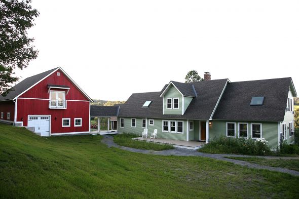 New home build with large two story green exterior and red barn in central Vermont