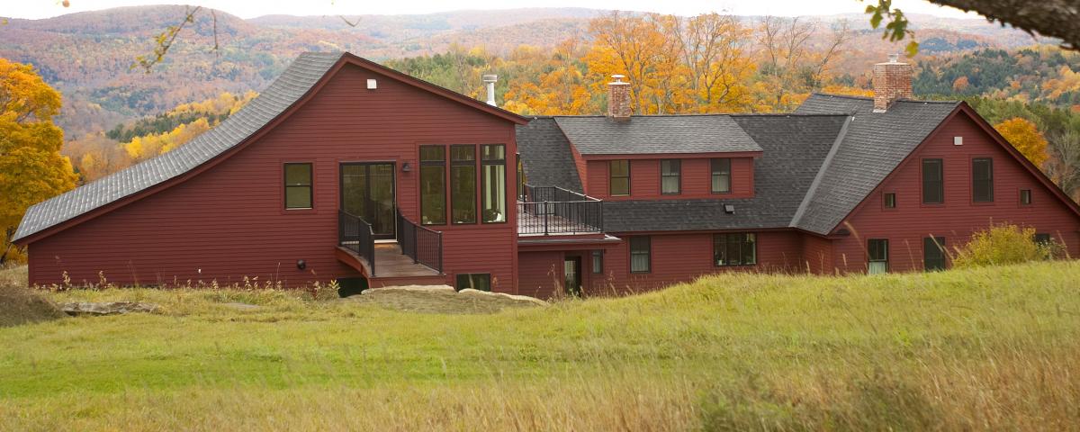 A sprawling red house after a full remodel set against hills in Central Vermont