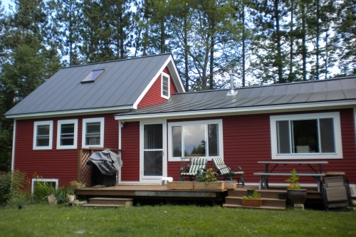 Rear of red house with white trim and wood deck after siding replacement remodeling project in central vermont