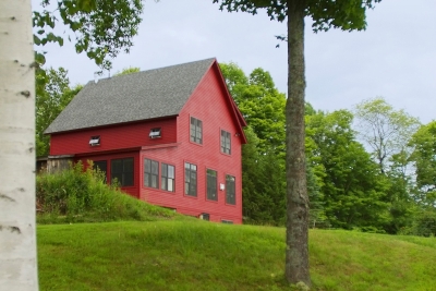 Red two story new home build perched on a hill in central Vermont