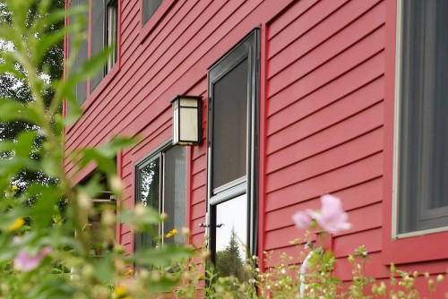 A view through a flower bed of a side door of a fully remodeled home in central vermont by allied building contractors