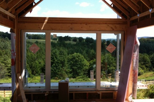 Unfinished living area during home build project looking out over green forested central vermont landscape