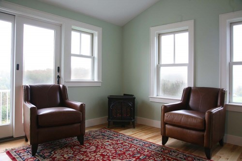 Living area with plush red chairs and green efficient windows looking out over central vermont hills in new home build