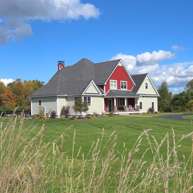 front exterior of a red and beige home with a large front yard