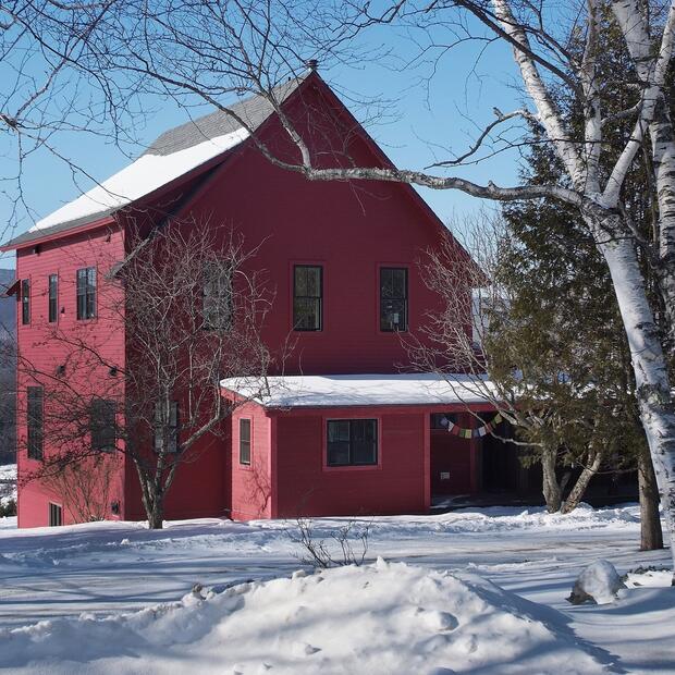 red house in a snowy landscape, framed by bare birch trees