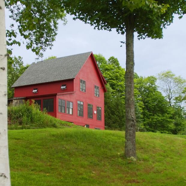 red home with black windows, nestled in a serene countryside setting