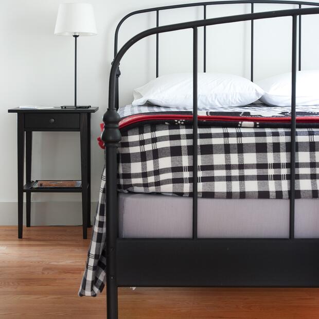 minimalist bedroom featuring a black frame bed and plaid bedding.