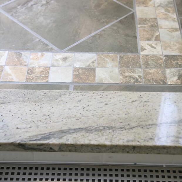 textured stone tile flooring with intricate patterns and a sleek granite step