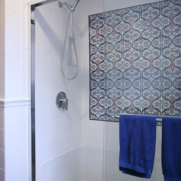 shower with a blue patterned tile accent and glass sliding doors