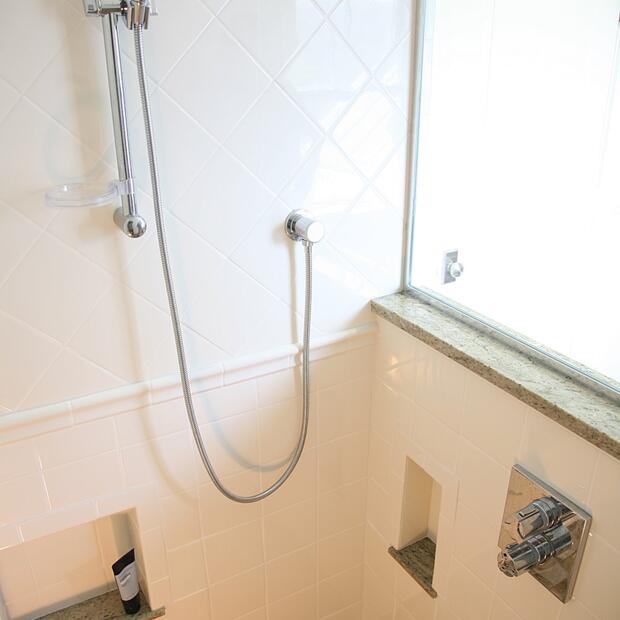 modern tiled shower with a handheld showerhead and built-in storage niches