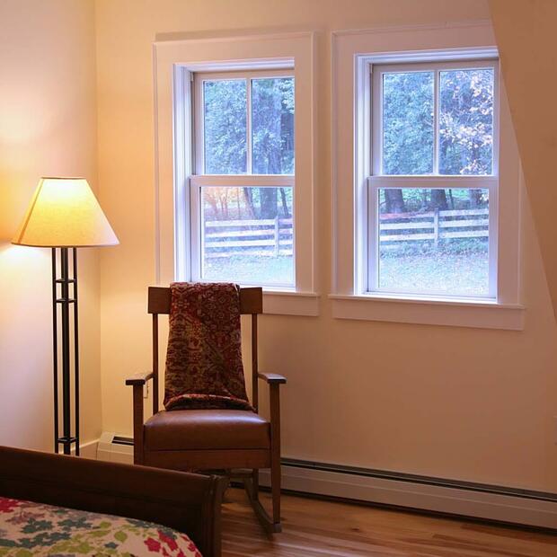 warm bedroom corner with a rocking chair, floor lamp, and window view