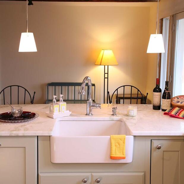 kitchen island with a farmhouse sink, marble countertop, and hanging lights