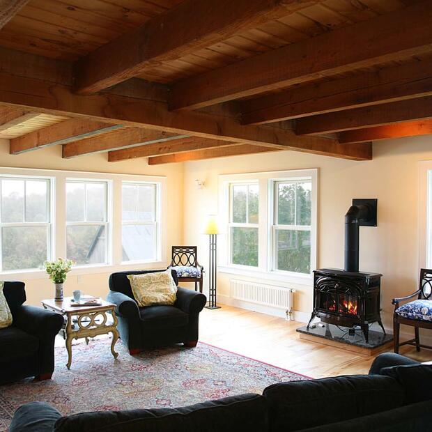 living room with exposed beams, a woodstove, and large windows