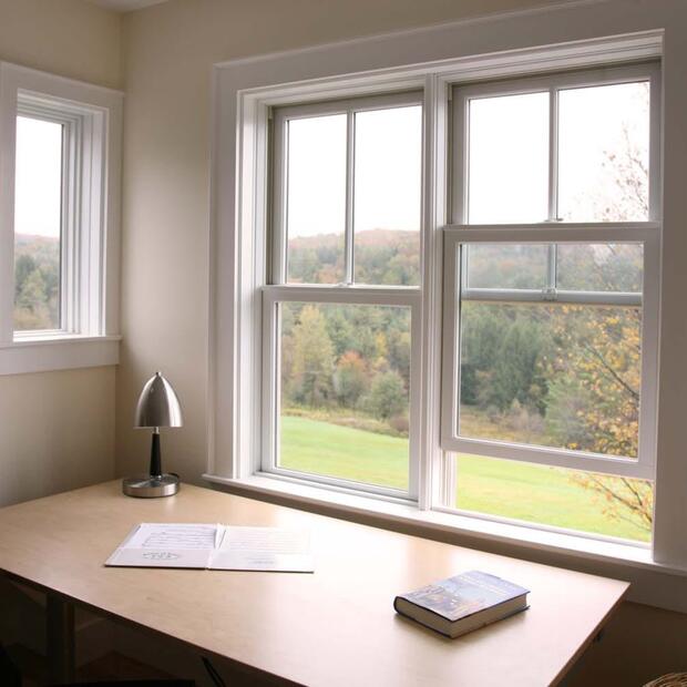 workspace featuring a desk, reading lamp, and large windows overlooking nature