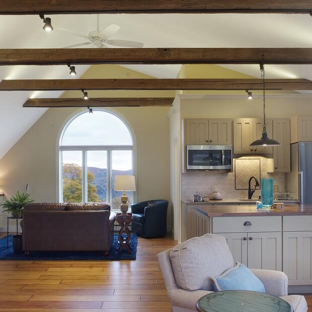 spacious loft with a modern farmhouse kitchen, exposed beams, and arched window views