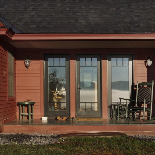 front porch with a rocking chair on a red farmhouse overlooking foggy hills