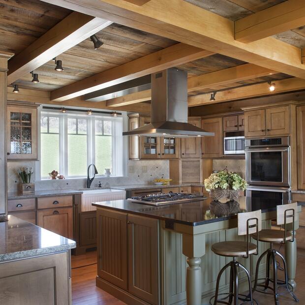 farmhouse-style kitchen featuring exposed beams, stainless steel appliances, and cozy decor