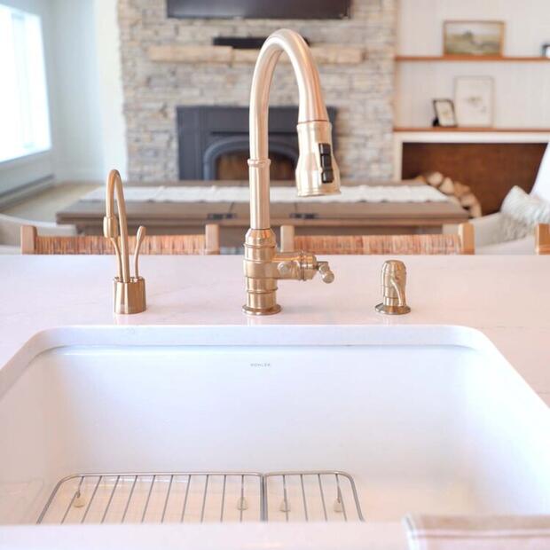 modern kitchen with a gold faucet, white sink, and cozy living room in view