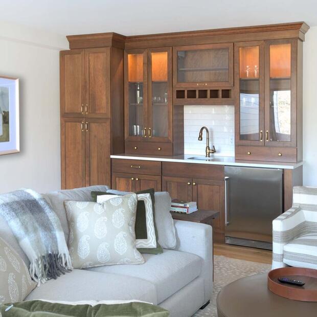 modern living space with a warm-toned wet bar, comfy sofa, and striped chair